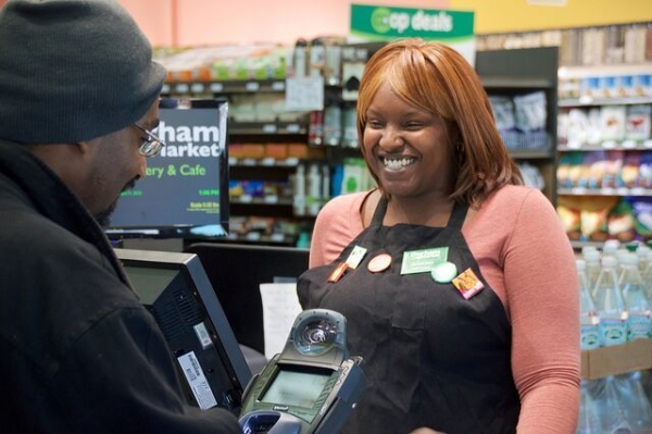 Black woman operating a cash register at a grocery.